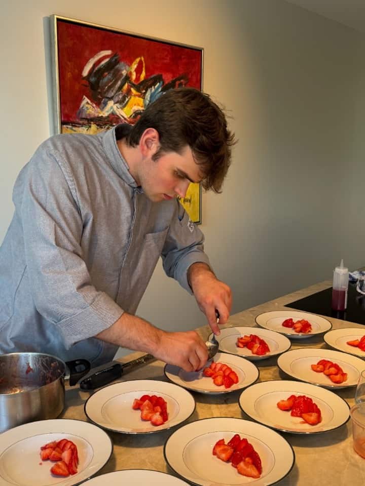 Chef die zorgvuldig aardbeien dresseert op dessertborden